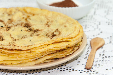 Yellow fresh pancakes served on the plate with cocoa sugar