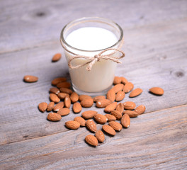 Almond milk in glass with almonds on wooden table