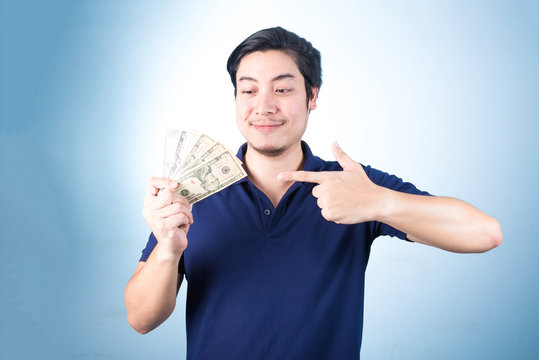 Asian handsome man holding money while standing on blue backgrou
