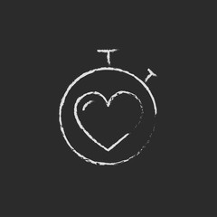 Stopwatch with heart icon drawn in chalk.