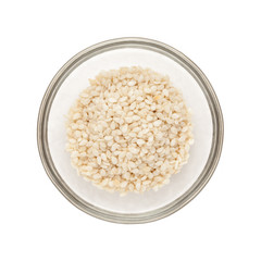 Top view of Organic Sesame white (Sesamum indicum) half filled in glass bowl isolated on white background.