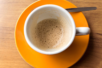 empty coffee cup with rest of cappuccino on an orange saucer