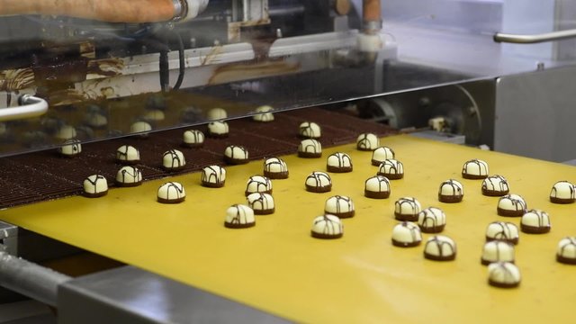 Fliessband mit Pralinen in einer Fabrik f&uuml;r S&uuml;&szlig;waren // Conveyor with chocolates in a factory of food industry