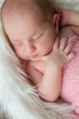7 day old newborn baby girl sleeping in a bowl with light pink background