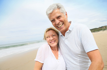 Obraz premium Married senior couple having fun walking in the beach