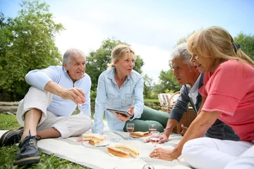 Schilderijen op glas Group of senior people enjoying picnic on sunny day © goodluz
