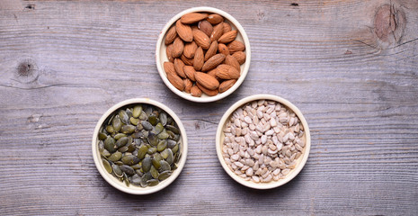 Sorted diferent seeds in white bowls on wooden background