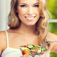 Woman eating salad, indoors