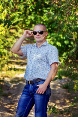 Naklejka na ściany i meble Portrait of handsome man in sunglasses standing in the park 
