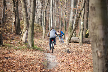 Two children on bicycles in autumn forest