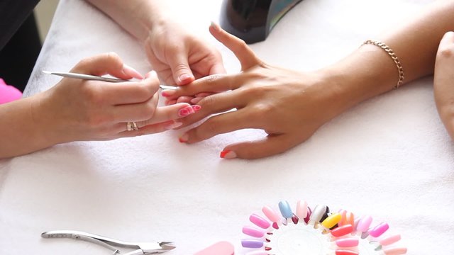 Cropped image of manicurist removing cuticle from the nail of woman at salon.