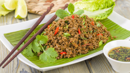 Larb - Lao minced beef salad with fish sauce, lime juice, roasted ground rice and fresh herbs served with lettuce leaves for wraps.