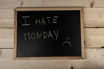 Lavagna con scritta " I hate monday" su sfondo di legno