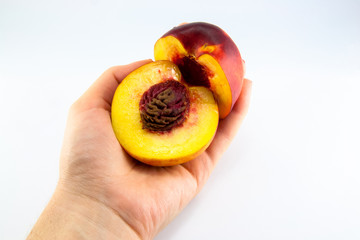 hand with a fresh juicy peach split in half isolated