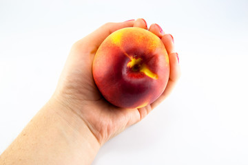 hand with a fresh juicy peach split in half isolated