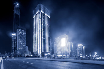 asphalt road near skyscrapers at night