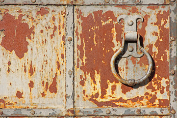 Old rusty metal gate with handle ring.