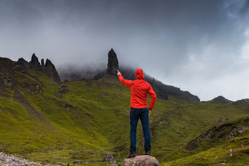 Man pointing to the Old Man of Storr natural monument. Scotland