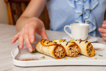 Woman eating Sicilian cannoli with coffee