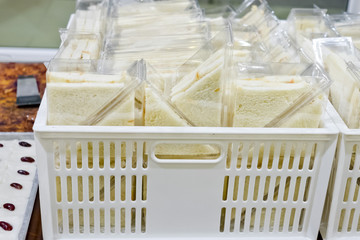 Fototapeta na wymiar Cut platter of sandwich triangles in plastic box ready for sell
