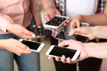 Many hands holding mobile phones close up