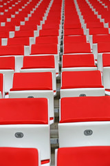 Obraz premium Czerwone fotele dla kibiców na sektorze trybuny nowoczesnego stadionu piłkarskiego