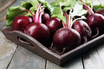 Young beets with leaves on wooden table close up