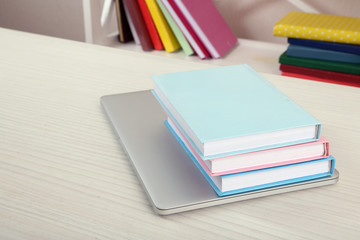Stack of books with laptop on table close up