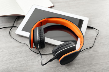 Obraz premium Headphones with tablet and notebook on wooden table close up