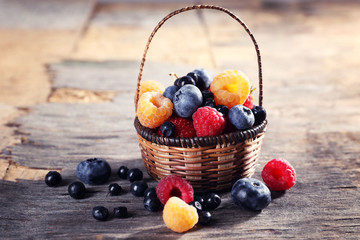 Sweet tasty berries in basket on wooden table close up