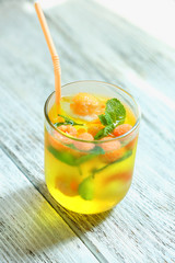 Glass of cold refreshing summer drink with berries and ice cubes on table close up