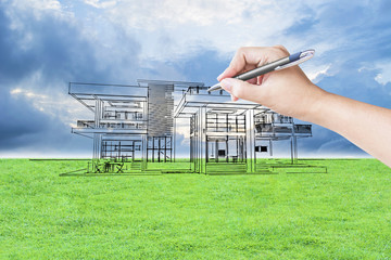 architect hand drawing a house on the grass field and sky background