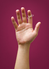 Hand with remider string isolated on red purple plum background