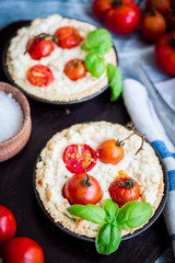 quiche with goat cheese, cherry tomatoes and basil on blue woode