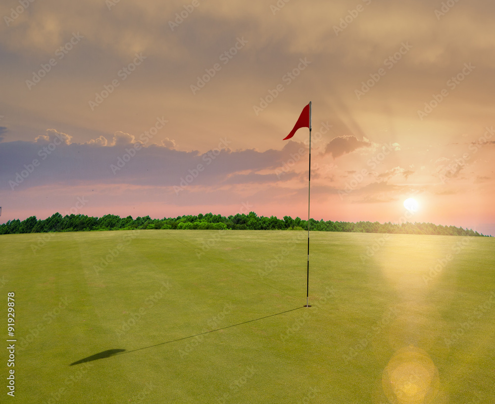 Wall mural red flag in a golf course during sunset