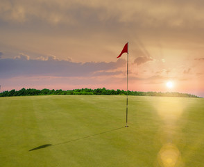 Obraz premium Red flag in a golf course during sunset