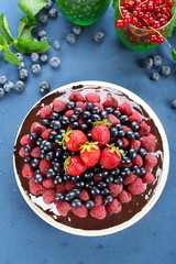 Delicious chocolate cake with summer berries on blue tablecloth, top view