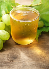 Glass of cool grape juice on wooden table, closeup