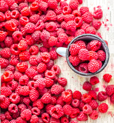 fresh red raspberries in a metal mug and placer, top view