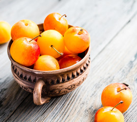 Fresh yellow plums in pottery on gray wooden table, rustic, farm