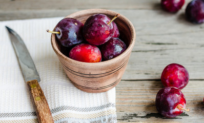 Fresh pink plum in pottery on gray wooden table, rustic