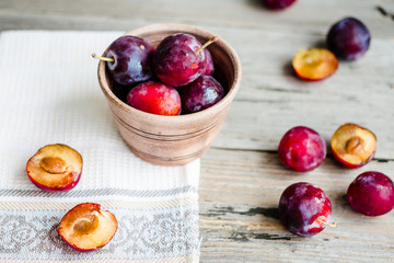 Fresh pink plum in pottery on gray wooden table, rustic