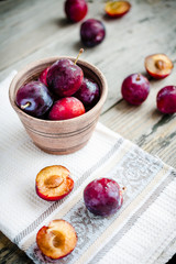 Fresh pink plum in pottery on gray wooden table, rustic