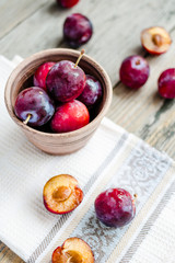 Fresh pink plum in pottery on gray wooden table, rustic