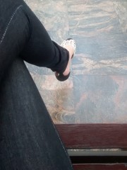 Pernas de uma moça sentada em um banco