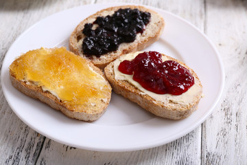 Fresh toast with butter and different jams on table close up