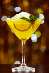 Glass of cocktail with ice on blurred lights background