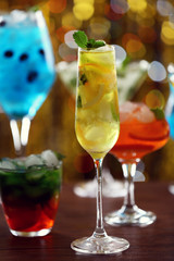 Glasses of cocktails with ice on blurred lights background