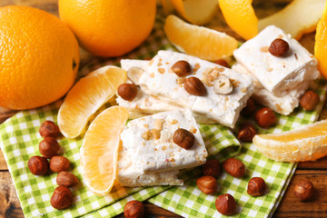 Sweet nougat with hazelnuts and oranges on table close up