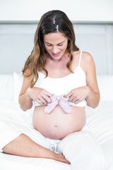 Happy woman with baby shoes on belly
